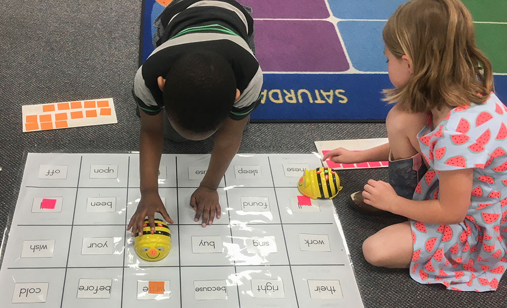 Two students work with Bee-Bots on a floor mat